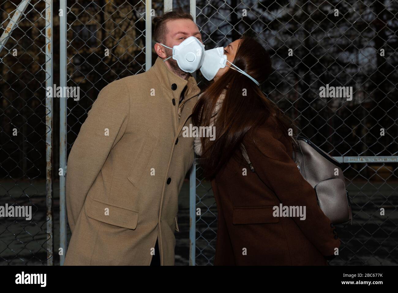 Jeune femme embrassant un homme dans la rue avec masque de protection foyer sélectif Banque D'Images
