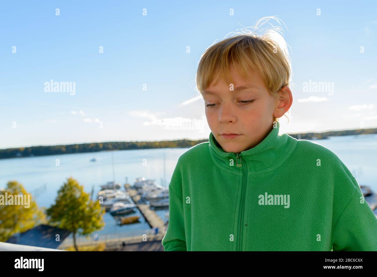 Jeune beau garçon pensant contre la vue de la jetée en bois près de la rivière Banque D'Images