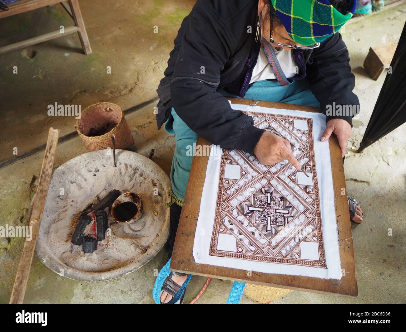 Une femme Hmong utilisant des modèles traditionnels pour peindre sur du tissu à Sapa, au Vietnam, qu'elle fera ensuite dans des sacs et d'autres objets d'artisanat Banque D'Images