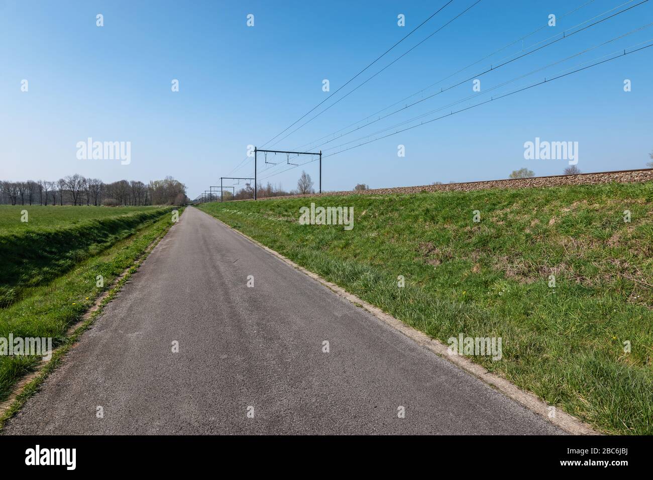 Route asphaltée près du chemin de fer dans la campagne belge. Banque D'Images