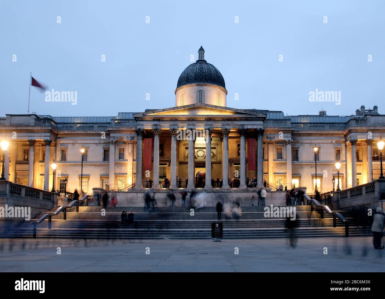 Exposition prolongée de la National Gallery, Trafalgar Square au coucher du soleil, avec des gens qui marchent sur la scène. Banque D'Images