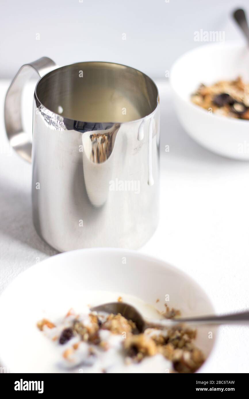 Un pot de lait et de boules de céréales sur fond de la table blanche. Manger Granola. Petit déjeuner sain. Banque D'Images