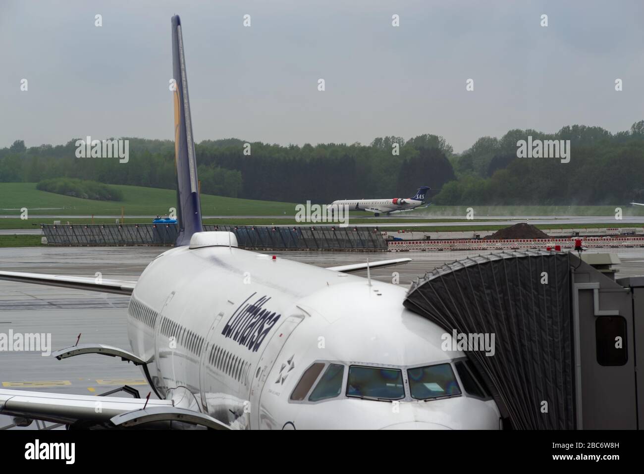 Hambourg, Allemagne - 28 avril 2019: Avion Lufthansa au pont d'embarquement de passagers (PBB) et avion SAS à l'atterrissage le jour des pluies à l'aéroport de Hambourg, Banque D'Images