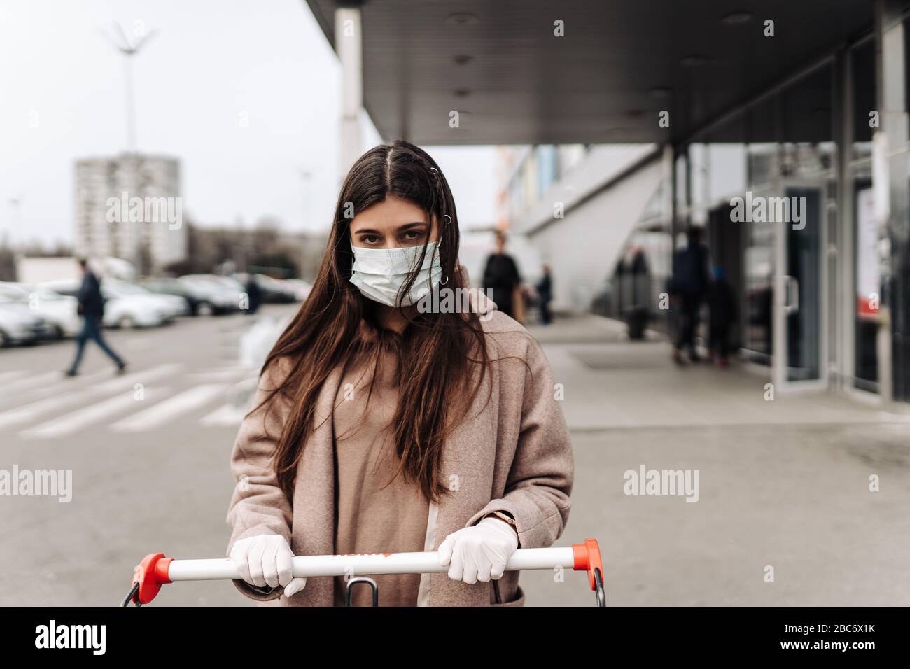 Jeune femme portant un masque de protection contre le coronavirus 2019-nCoV poussant un panier. Banque D'Images