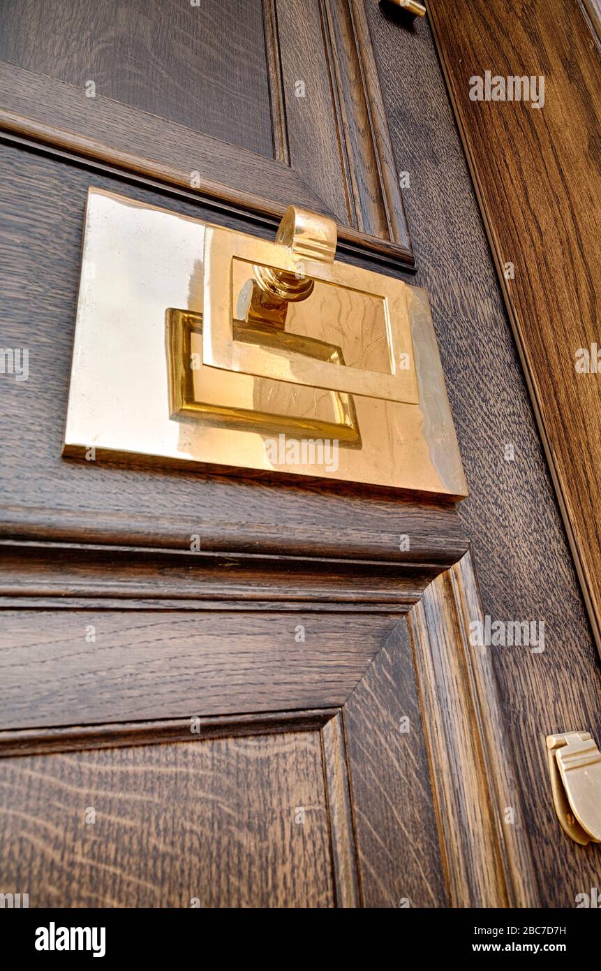 Une poignée en laiton, un knocker et un revêtement sur une porte en bois sombre Banque D'Images