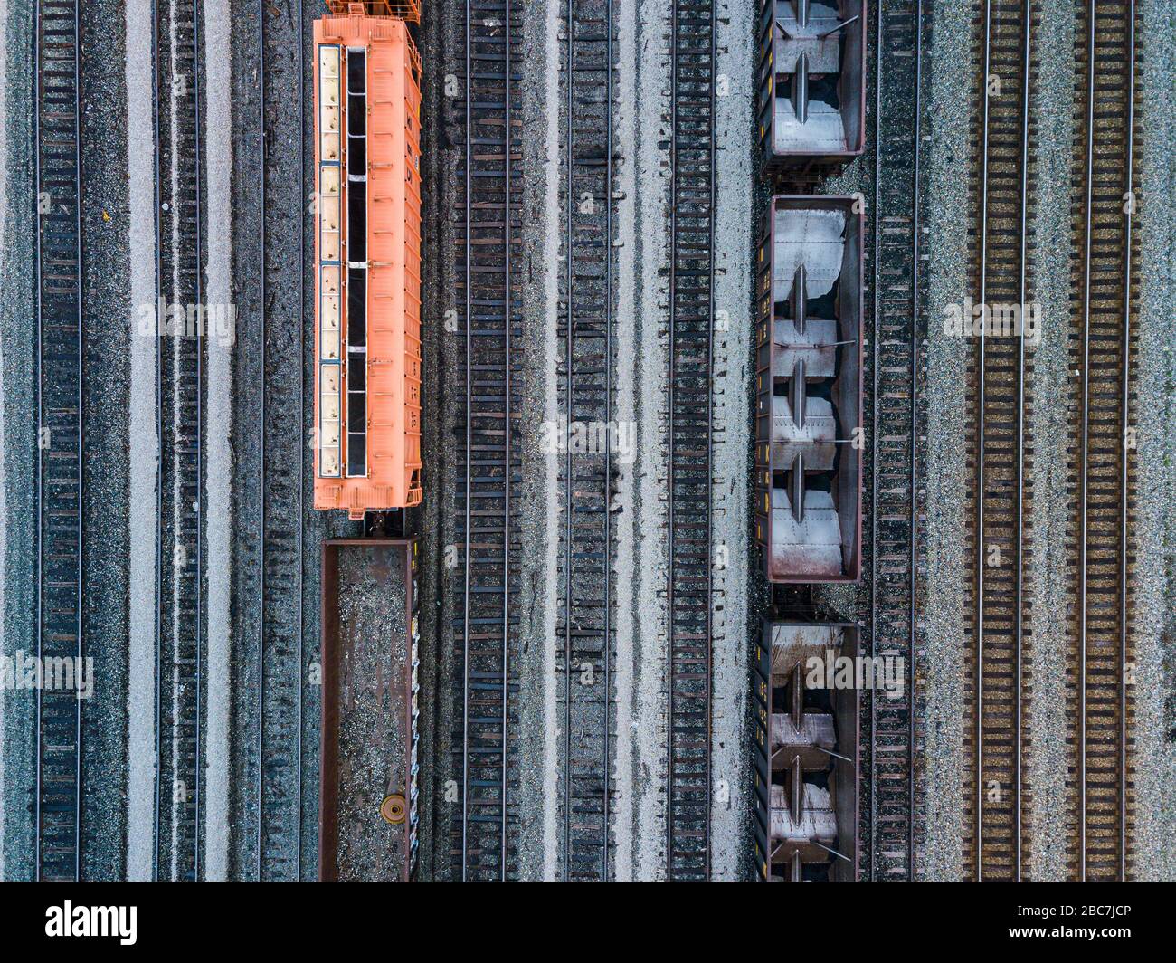 Prise de vue aérienne de wagons de chemin de fer, un debout avec une couleur orange, et des voies montrant la symétrie. Banque D'Images