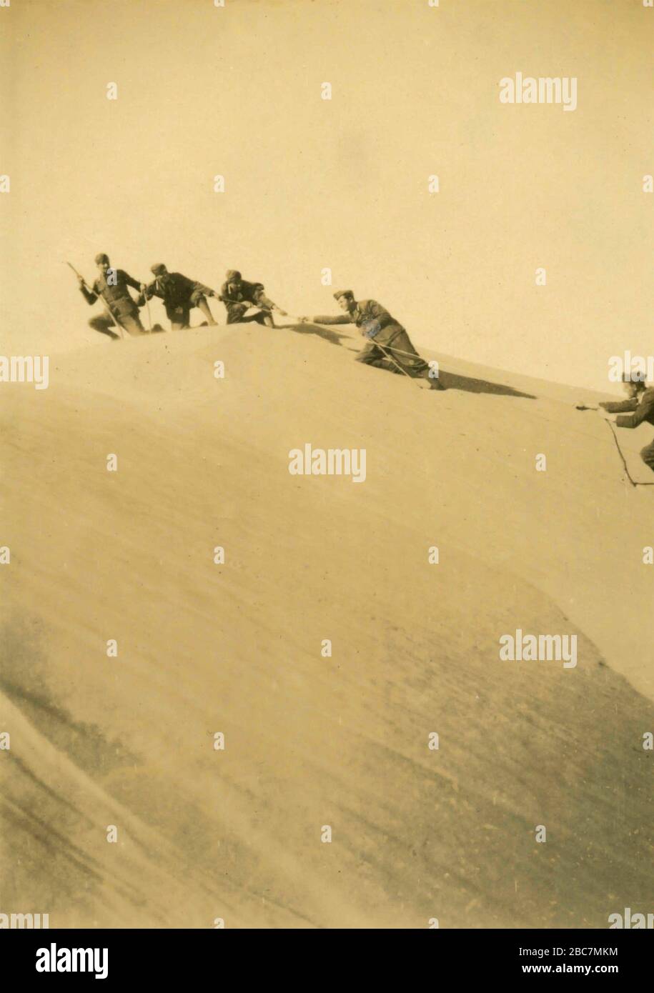 Soldats de l'armée royale italienne grimpant une dune dans le désert, colonies italiennes d'Afrique de l'est années 1930 Banque D'Images