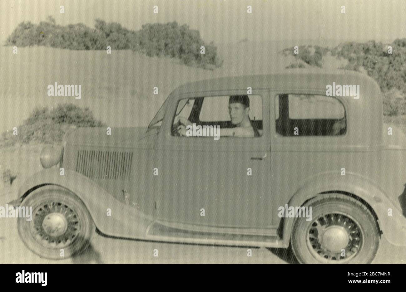 Homme conduisant une voiture Balilla FIAT dans le désert, Afrique de l'est colonies italiennes, Gurgussum Massawa, Erythrée 1938 Banque D'Images