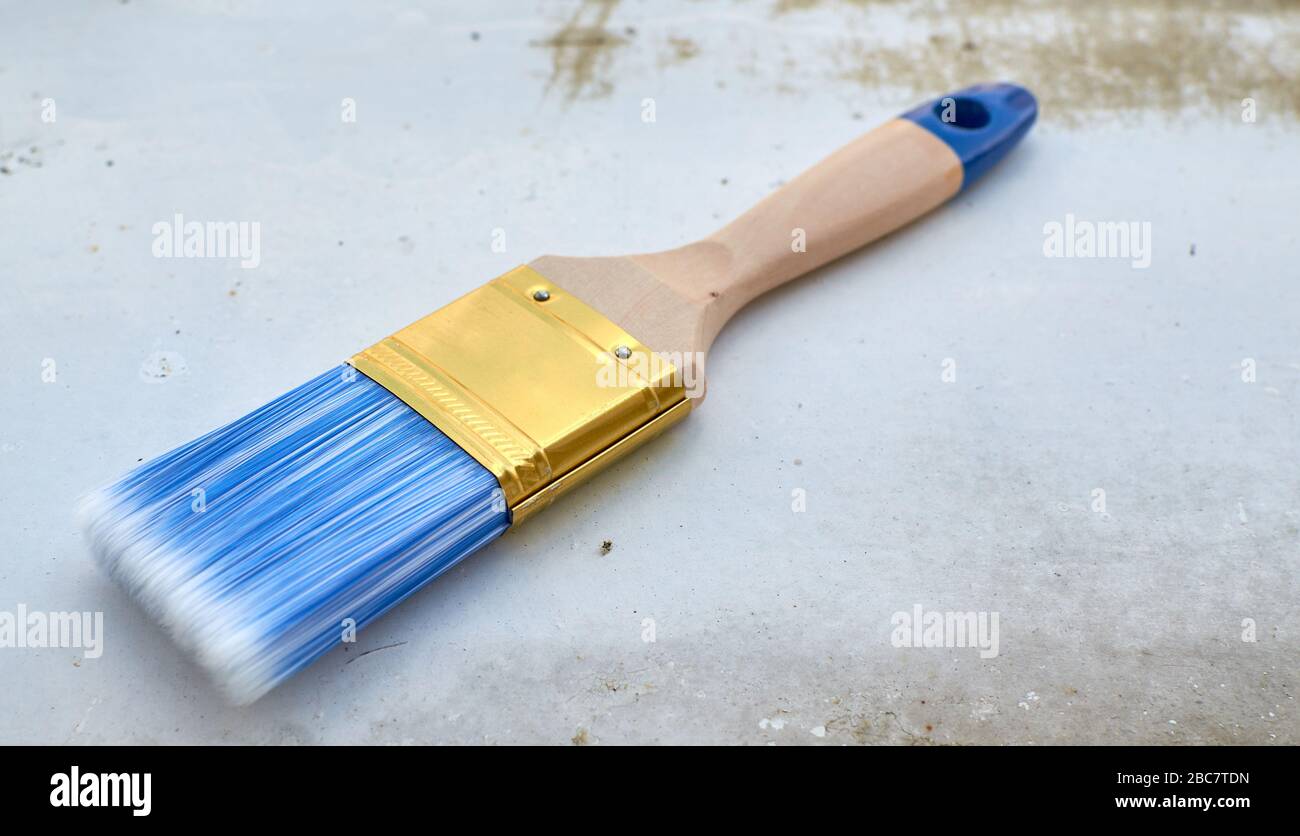 Nouvelle brosse en bois pour peindre avec des poils bleus sur une surface métallique ancienne Banque D'Images