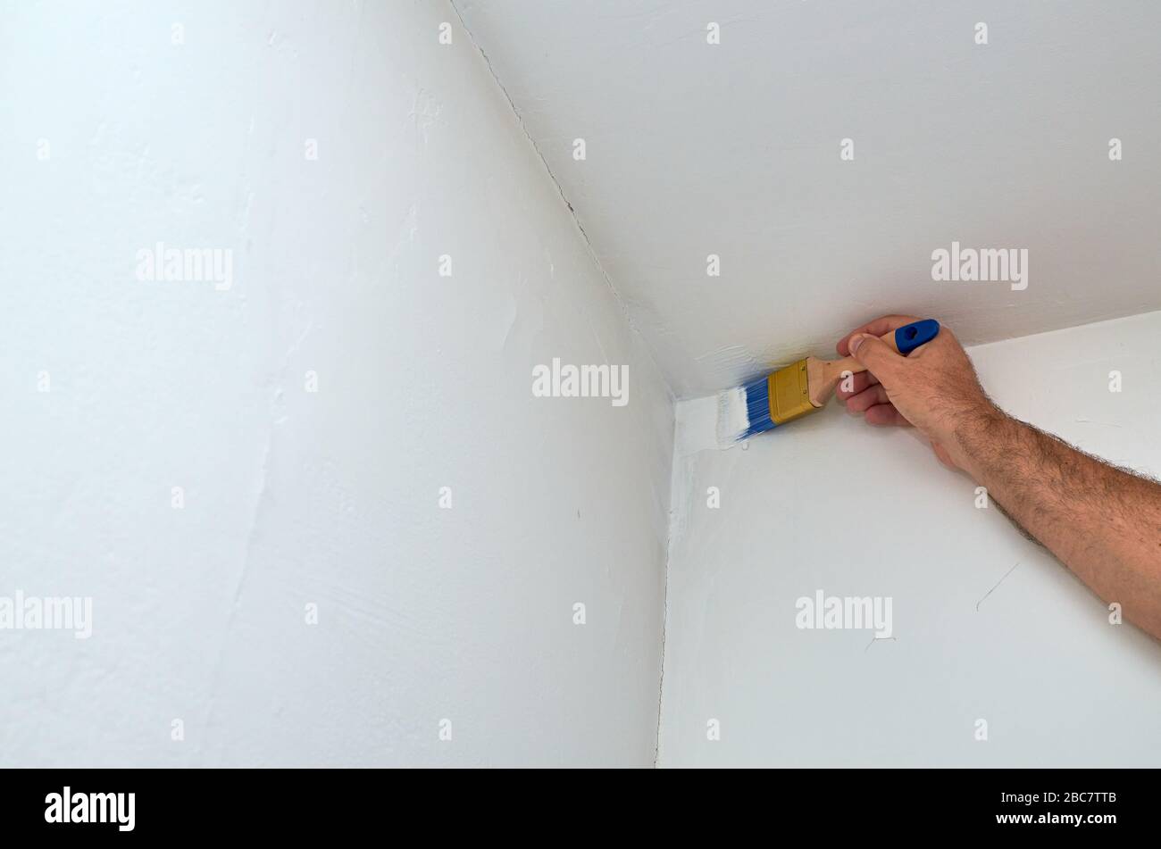 Main tenant le pinceau et le coin peinture d'un mur et d'un plafond Photo  Stock - Alamy