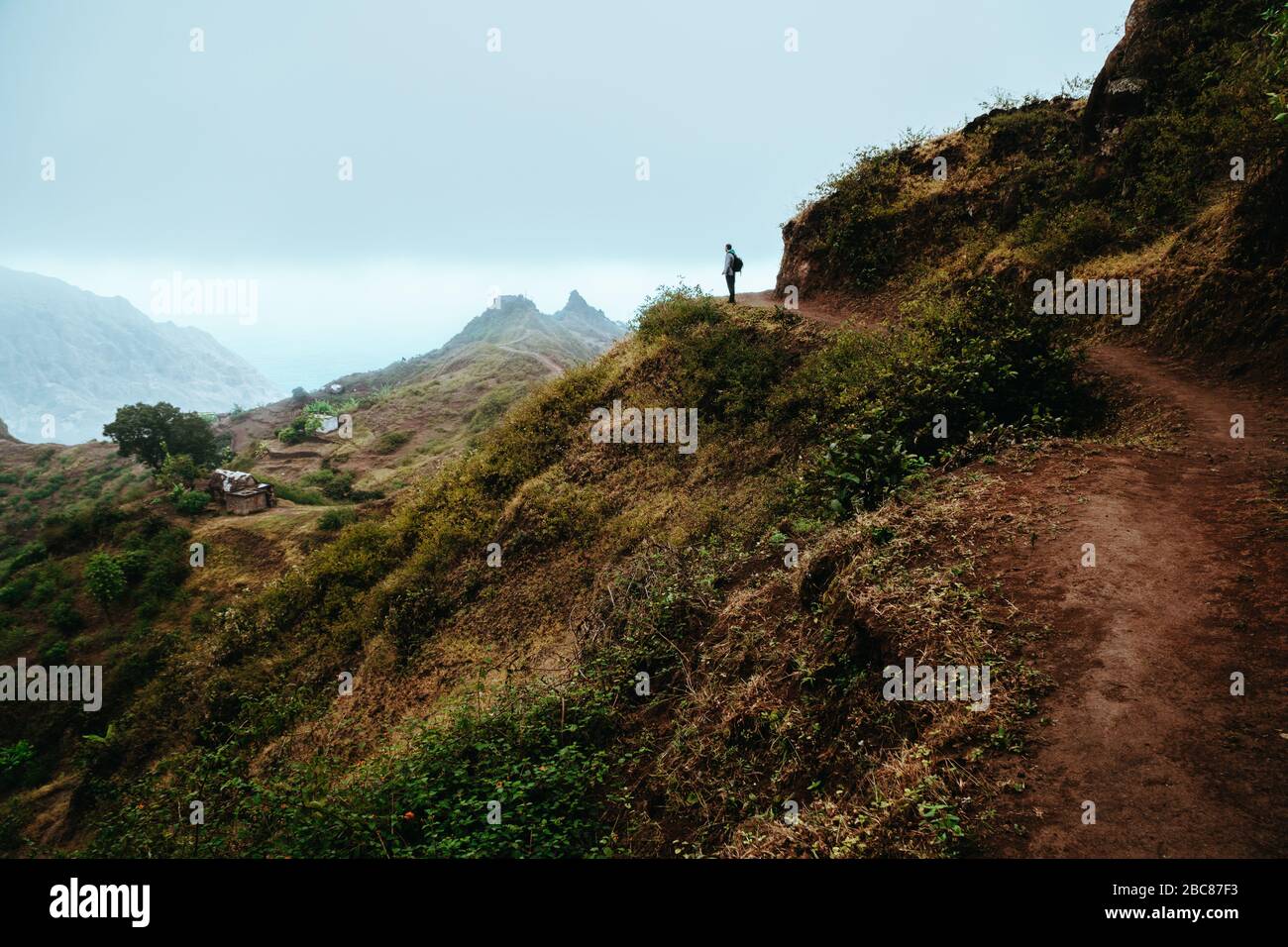 La silhouette de randonneur regarde dans la vallée et écoute le silence. Le brouillard et la brume s'accrochent au-dessus des pics de montagne sur le sentier de Pompas. Cap Santo Antao Banque D'Images