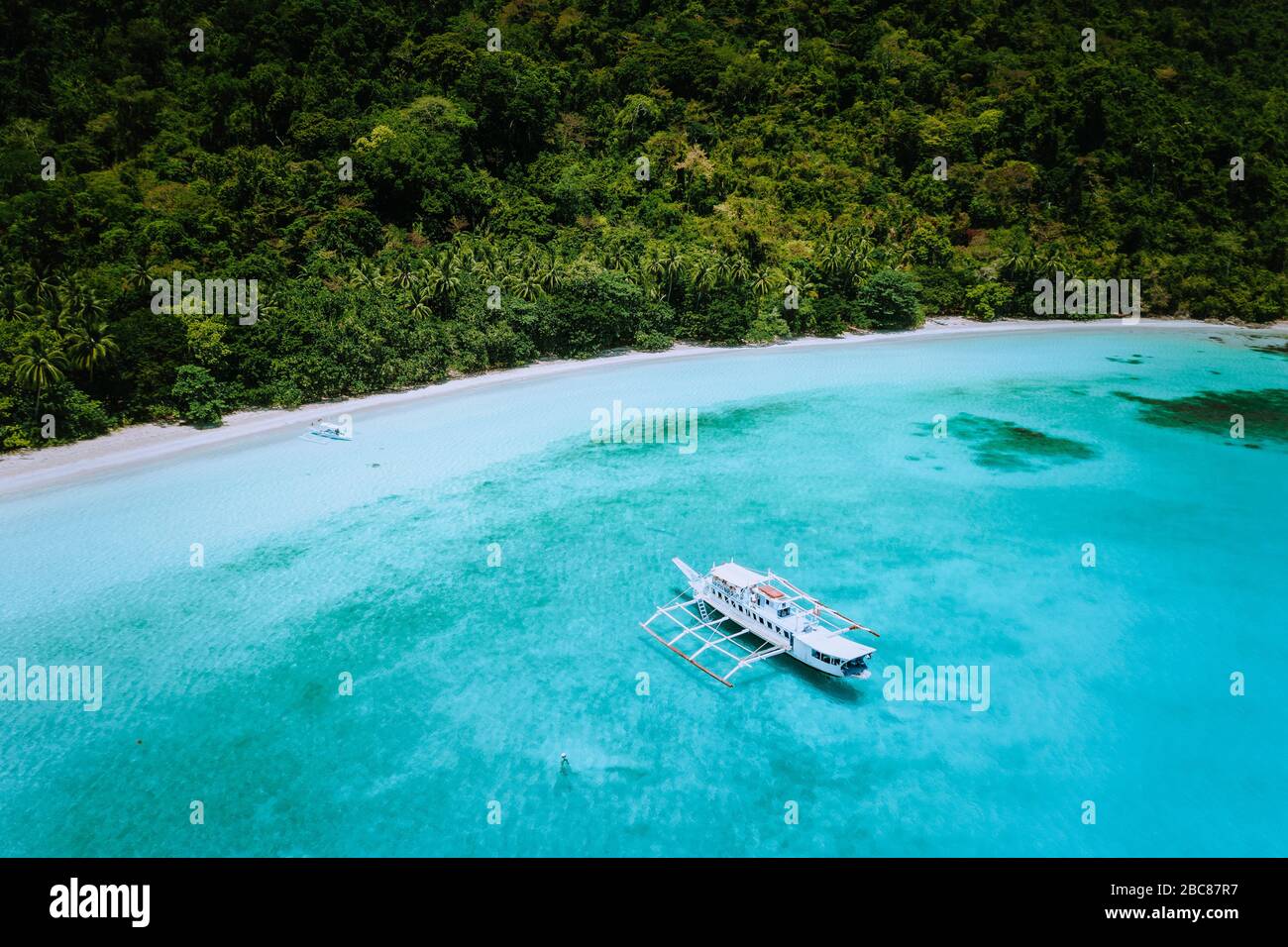 Vue aérienne sur une vaste plage de sable tropical avec forêt tropicale luxuriante et bateaux banca. Escapade rêve endroit brut paradis. Banque D'Images Vue aérienne sur une vaste plage de sable tropical avec forêt tropicale luxuriante et bateaux banca. Escapade rêve endroit brut paradis. Banque D'Images
