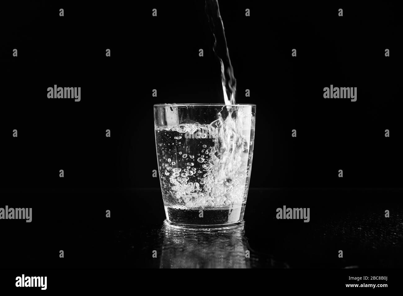 Verser de l'eau fraîche purifiée dans le verre sur le fond du miroir Banque D'Images