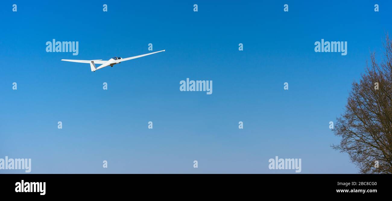 Glider blanc pur dans le ciel bleu clair survolant la cime. Concept de succès, réalisation d'un objectif élevé. Banque D'Images