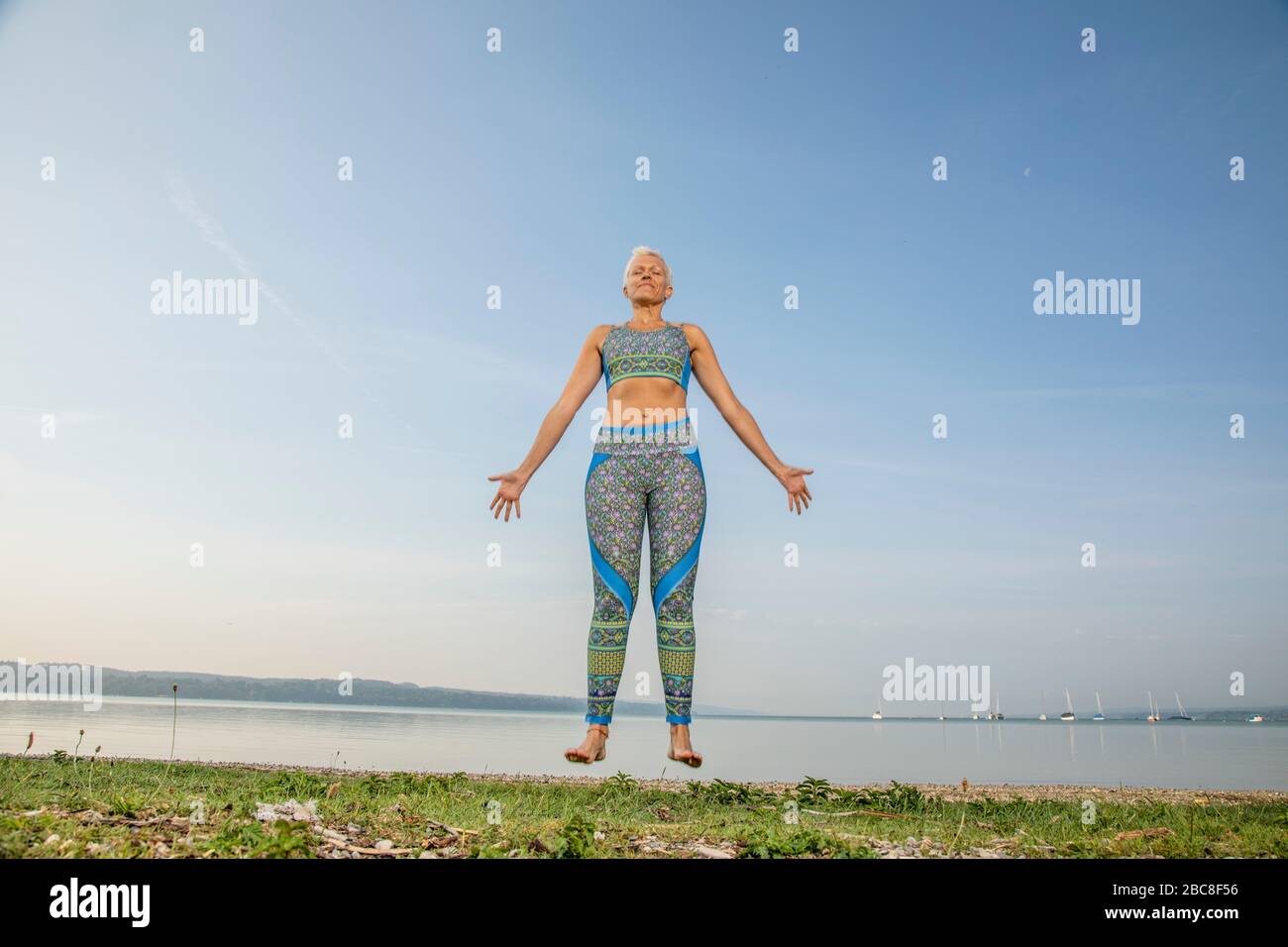 Méditation IKYA, femme dans les vêtements de sport gaiement au bord du lac Banque D'Images