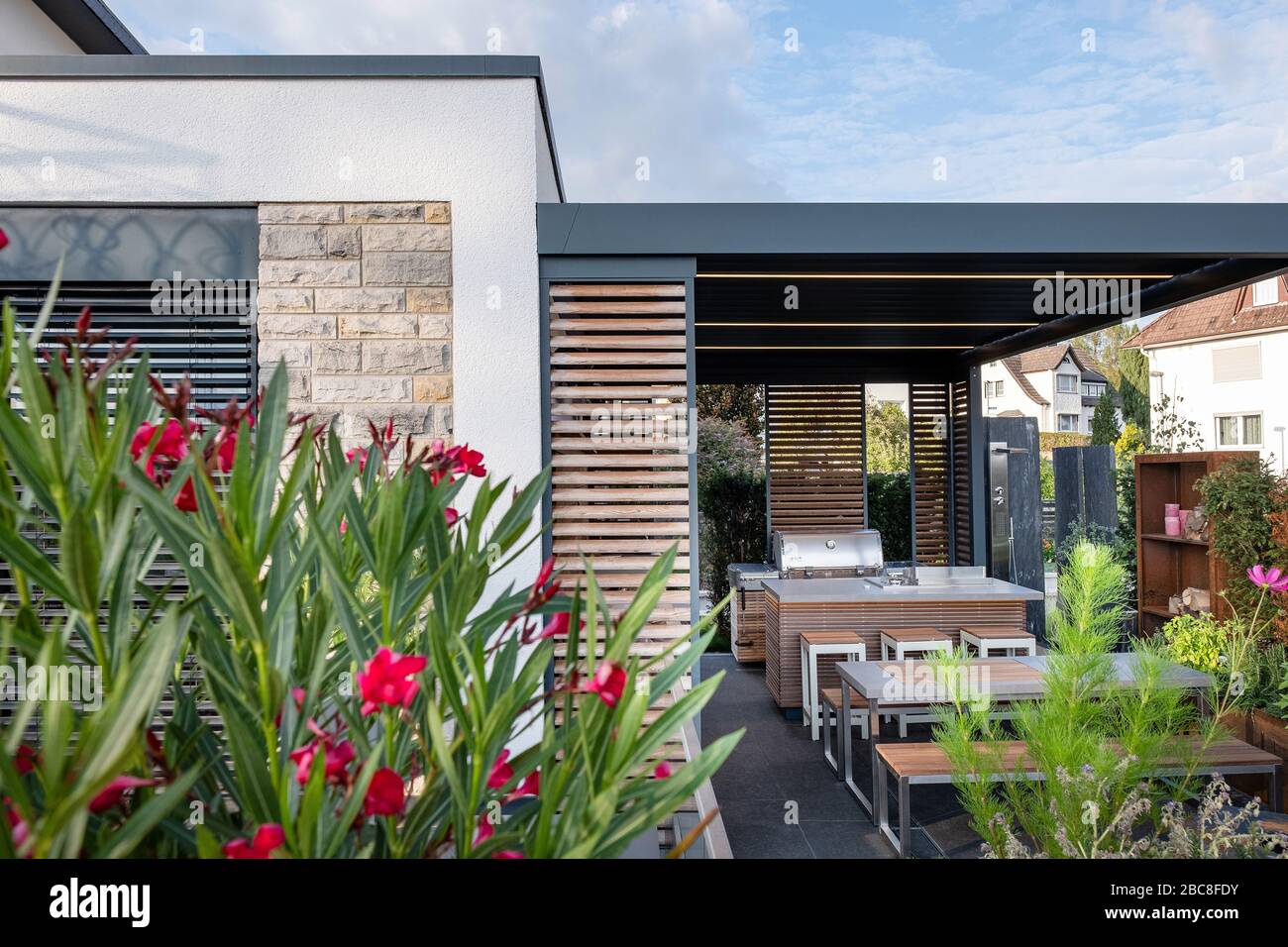 Terrasse couverte moderne avec cuisine extérieure, coin salon et cheminée avec orleander et panier à bijoux Banque D'Images