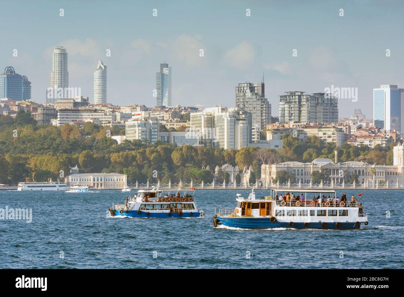 Istanbul, Turquie. Ferries sur le Bosphore. Palais Dolmabahce sur la rive droite. Bâtiments modernes derrière. Banque D'Images