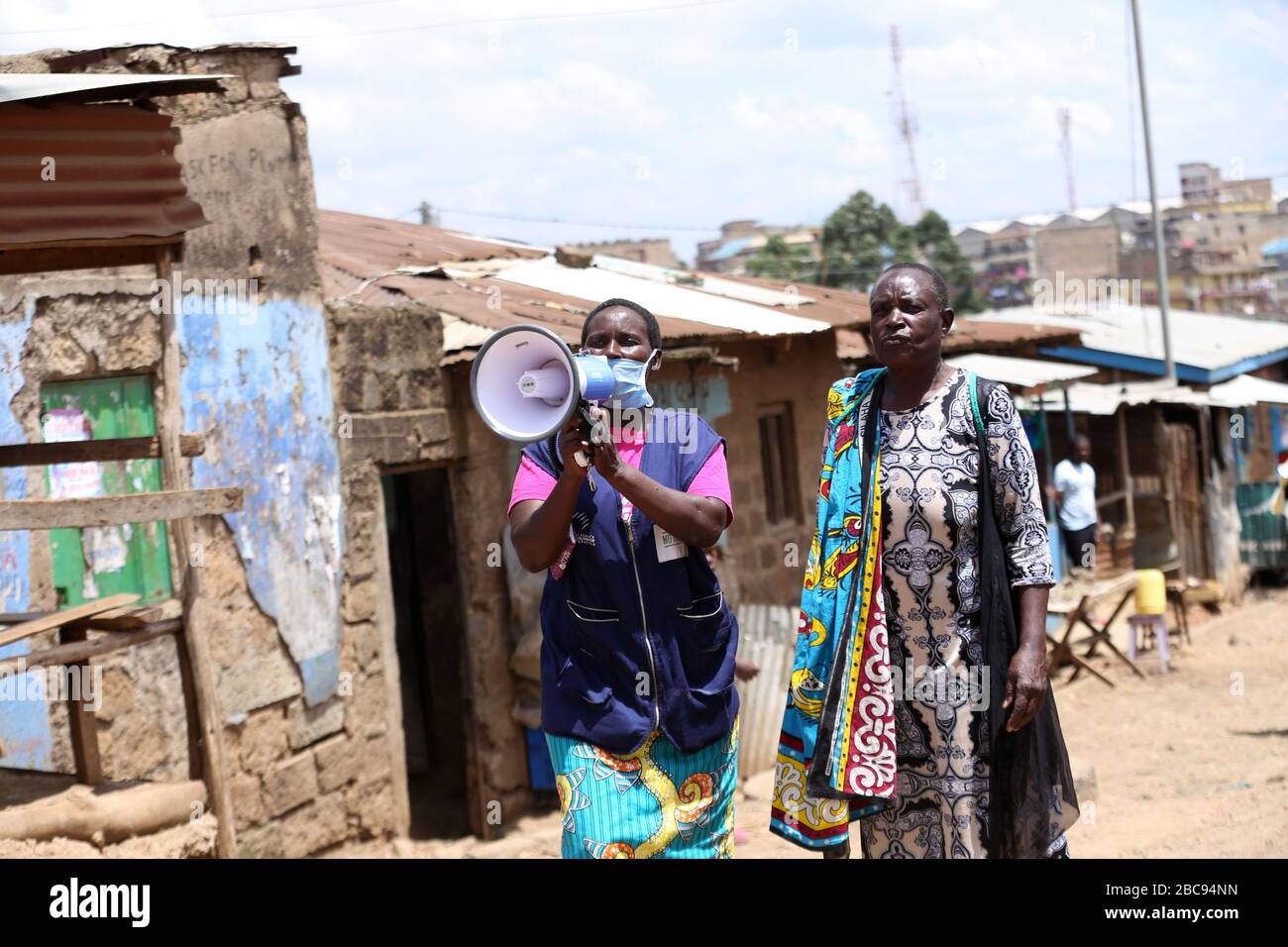 Un volontaire de santé traverse les rues en parlant à travers un mégaphone sensibilisant les habitants au sujet de Coronavirus dans les bidonvilles de Baba Dogo à Nairobi. Il y a plus de 2,5 millions de personnes vivant dans des bidonvilles de Nairobi qui, outre la pandémie, peuvent souffrir gravement des effets socio-économiques. Le gouvernement kenyan a annoncé des possibilités de verrouillage. La majorité des habitants vivent moins de deux dollars par jour, sans eau courante, réseau routier médiocre et pénurie alimentaire. Le Kenya a confirmé 122 cas de coronavirus et quatre décès. Banque D'Images