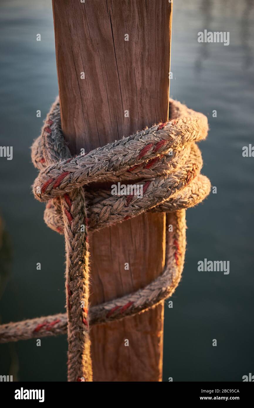 Photo au lever du soleil avec lueur dorée de Rope au quai sur la rivière en attendant que le bateau soit amarré. Banque D'Images
