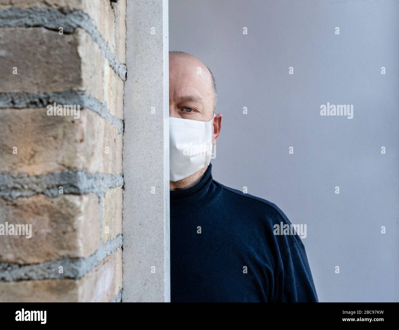 un homme qui quitte la maison avec un masque de protection sur sa bouche pendant la pandémie de coronavirus Banque D'Images