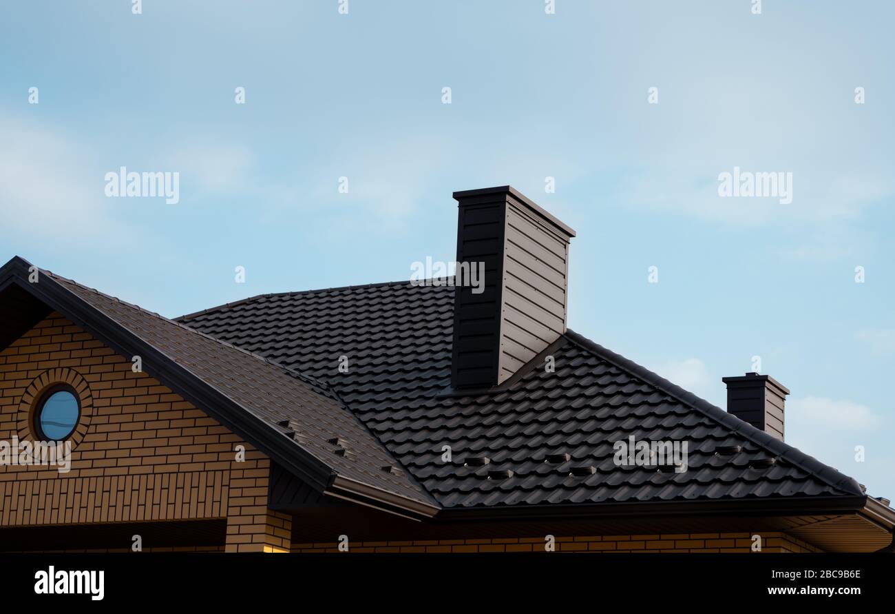 Toit en carreaux de métal marron. Tôles de toit en métal. Types modernes de matériaux de toiture. Toit de la maison, tuile de toit métallique contre le ciel bleu. Bâtiment. Banque D'Images