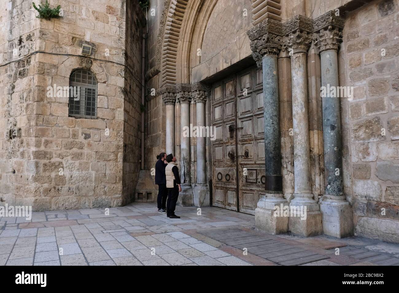 Les visiteurs se tiennent devant la porte fermée de l'Église du Saint-Sépulcre, au milieu de la crise pandémique Coronavirus COVID-19 dans la vieille ville de Jérusalem, Israël Banque D'Images