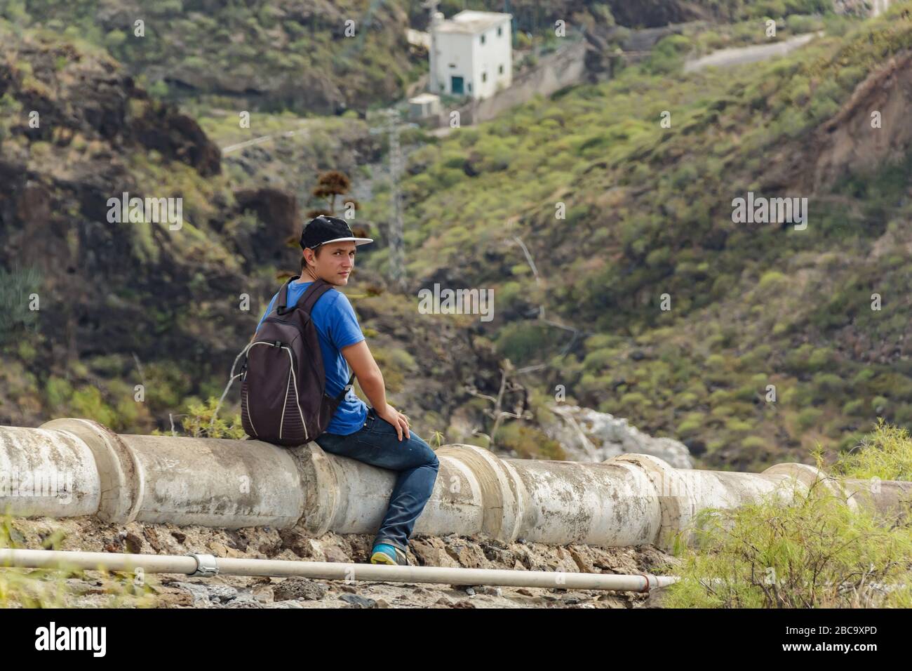 Un jeune homme avec un sac à dos sur l'aqueduc en béton dans le côté ouest de Tenerife près du village d'Adeje. Randonnée pédestre par le sentier de montagne Banque D'Images