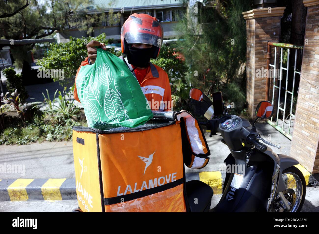 Antipolo City, Philippines - 2 avril 2020: Un transporteur charge des articles d'épicerie à livrer pour un client pendant le verrouillage ou la quarantaine communautaire due à Banque D'Images