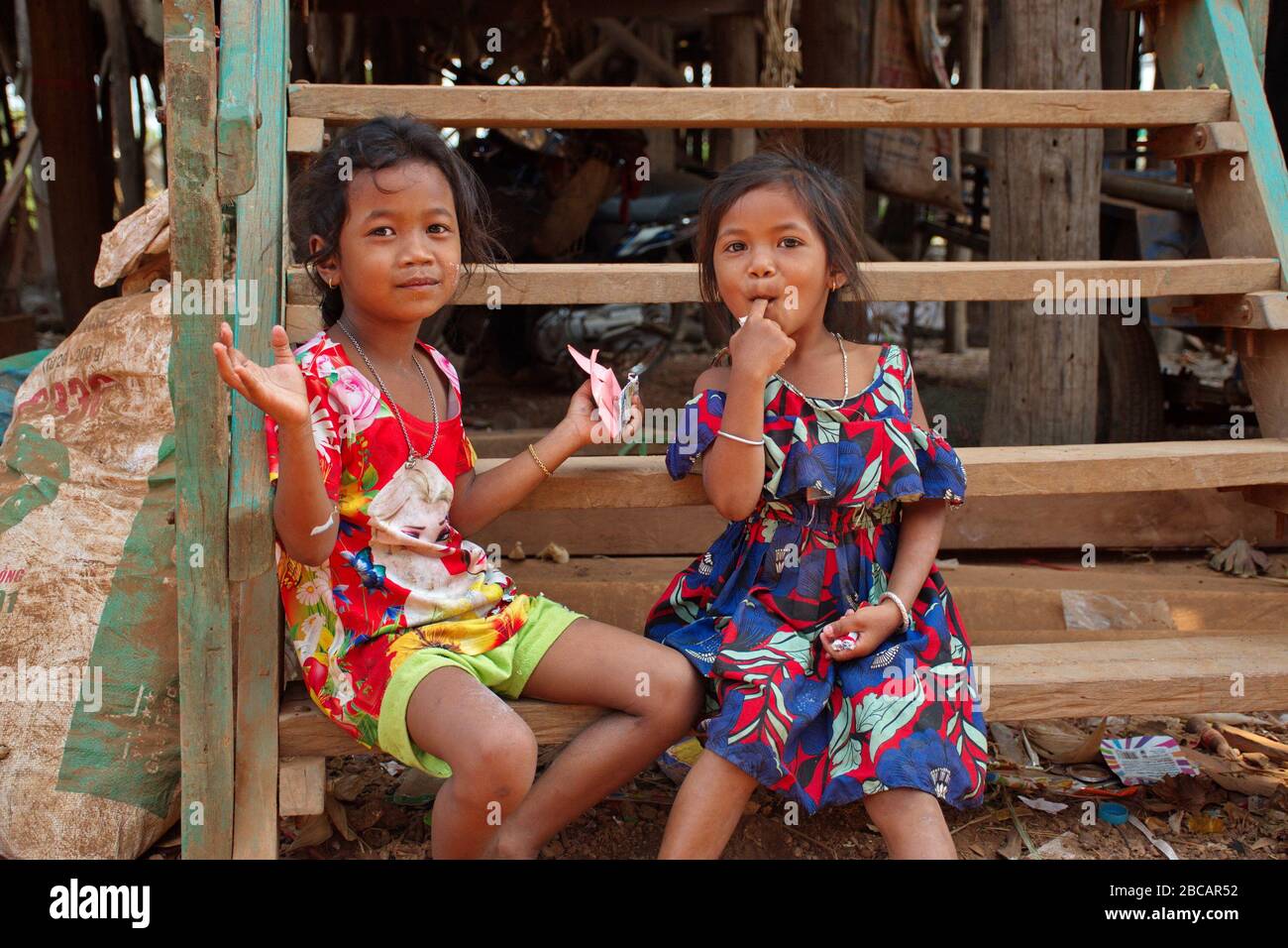 Portrait de jeunes filles cambodgiennes assis sur les escaliers de la maison dans le village de pêcheurs Banque D'Images