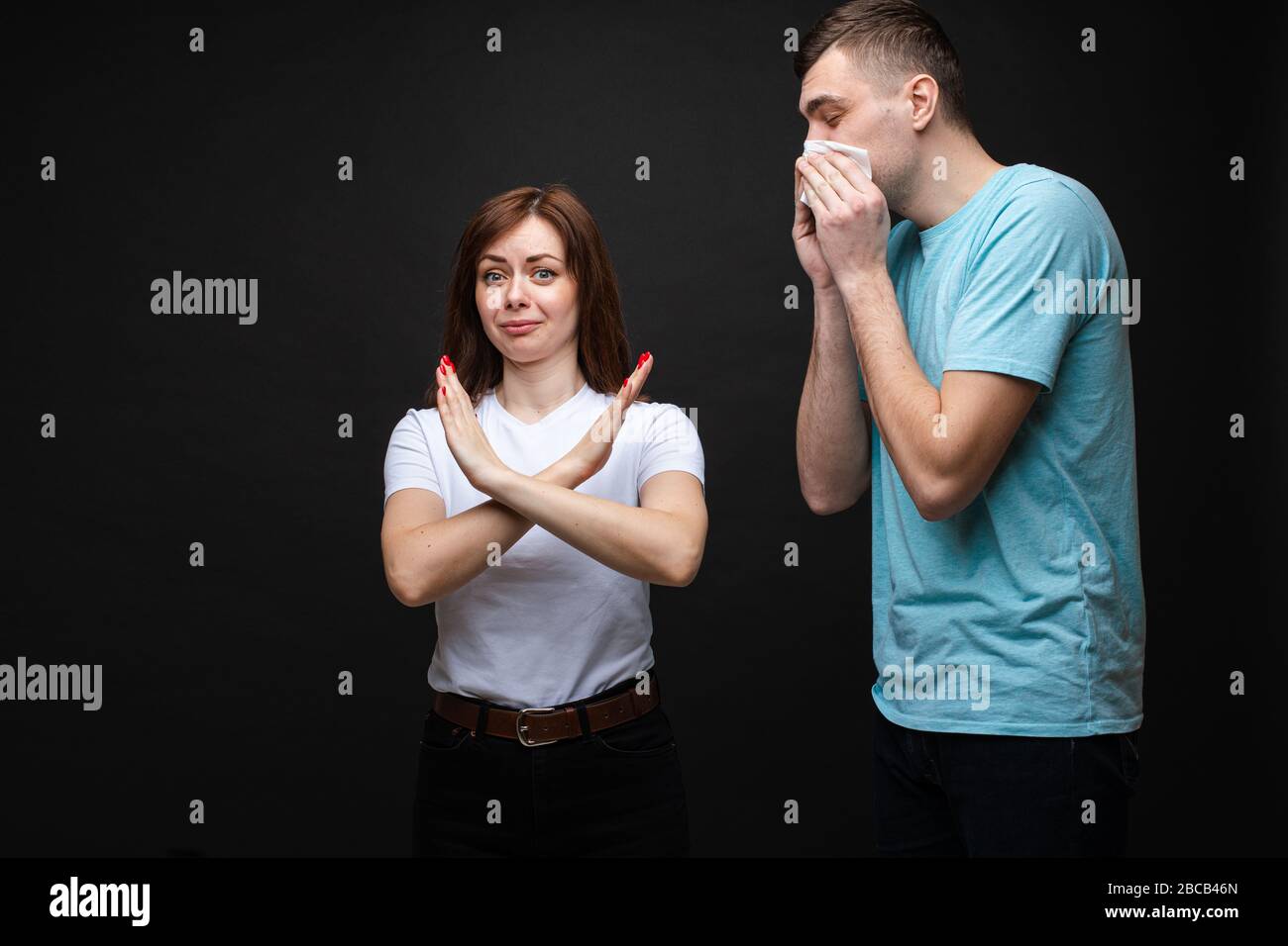 Jeune femme avec un geste d'arrêt et un homme éternuant. Banque D'Images
