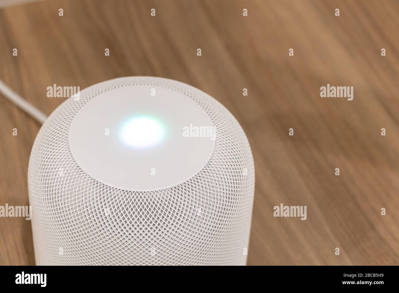 HomePod Apple blanc sur une table avec lumière Siri allumée sur le dessus. Banque D'Images