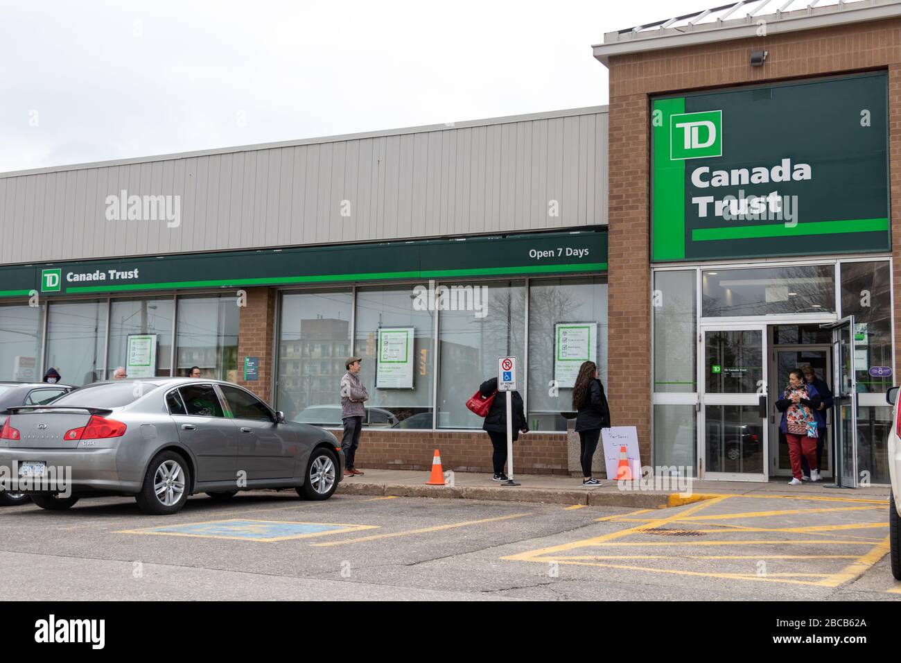 La succursale bancaire TD Canada Trust considérée comme des clients sont alignées à l'extérieur de la pratique de l'éloignement social, en attendant d'y aller. Banque D'Images