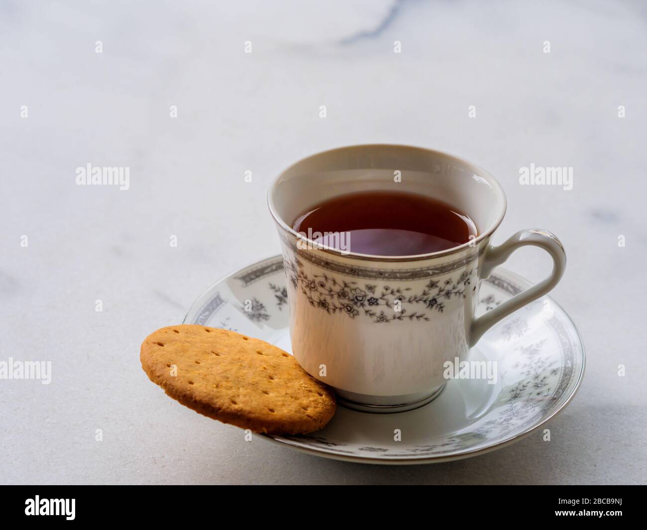 Thé anglais dans une tasse en porcelaine fine de chine avec un biscuit digestif. Pause-thé, concept thé de l'après-midi Banque D'Images