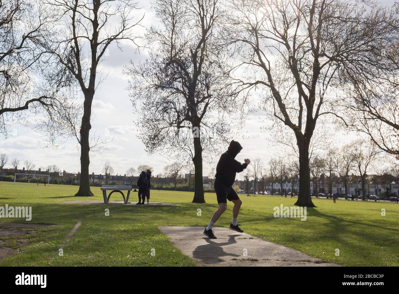 Alors que la deuxième semaine du maintien du Coronavirus se poursuit et une semaine avant Pâques, lorsque le Premier ministre Boris Johnson rappelle aux Britanniques de rester localement et de ne pas se rendre dans des lieux de beauté, le nombre de morts au Royaume-Uni atteint 2 921, avec 1 million de cas de Covid-19 dans 181 pays. Michial, un poids moyen de Brooklyn spars avec une application de boxe sur son téléphone en après-midi soleil et les températures printanières à Ruskin Park à Herne Hill, 3 avril 2020, dans le sud de Londres, Angleterre. Banque D'Images