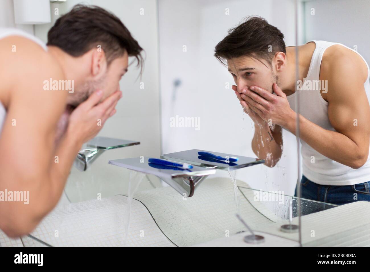 Jeune homme lave-visage dans salle de bains Banque D'Images