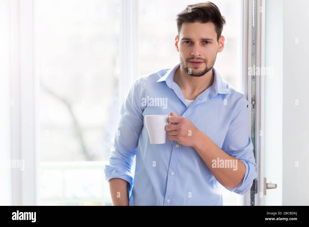 Homme buvant une tasse de café près de la fenêtre Banque D'Images