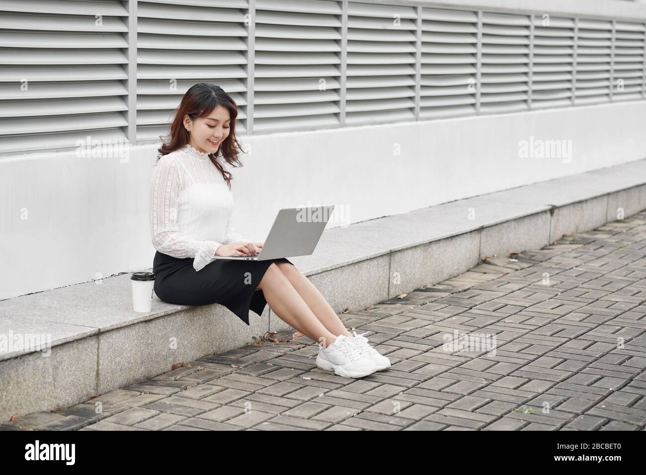 Une femme joyeuse qui utilise un ordinateur portable assis sur les traces Banque D'Images