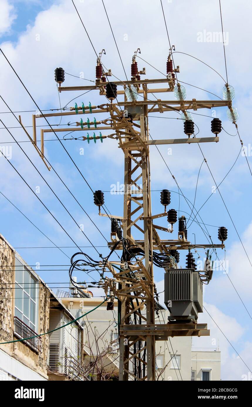 Paysage urbain avec vue sur une ligne d'alimentation haute tension et un mât avec transformateur électrique abaisseur Banque D'Images