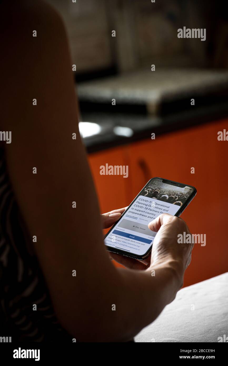 Femme qui vérifie certaines informations concernant la COVID-19 sur l'application de l'Organisation mondiale de la santé sur son mobile Banque D'Images