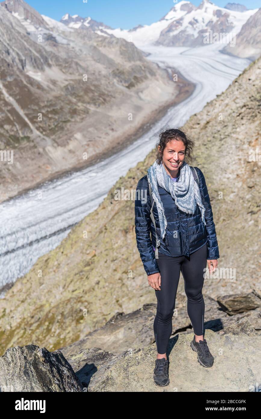 Jeune femme caucasienne qui pose pour la caméra, avec le Grand glacier d'Aletsch derrière elle Banque D'Images