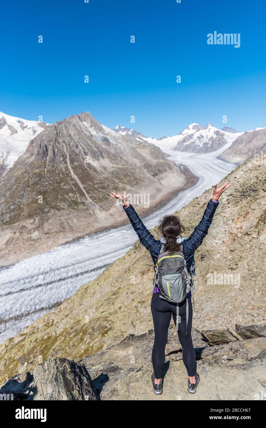 Vue de derrière une femme avec ses bras élevés regardant le glacier d'Aletsch du point de vue d'Eggishorn, Alpes bernoises, Valais du canton, Suisse, Europe Banque D'Images