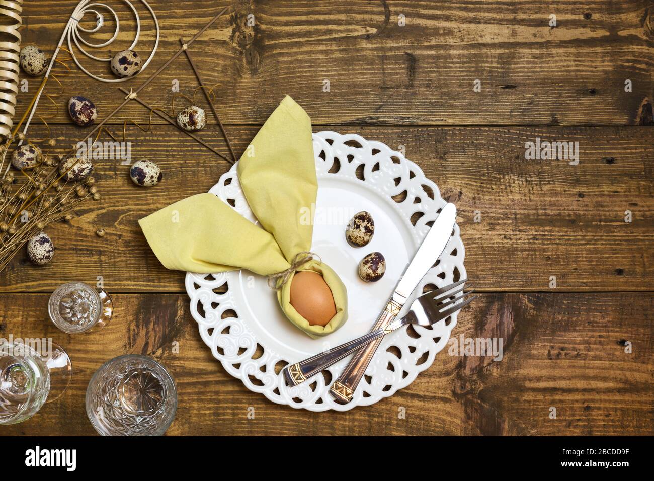 Table de Pâques festive avec œufs en serviette comme le lapin de Pâques et œufs de caille sur fond rustique. Vue de dessus avec espace de copie. Banque D'Images