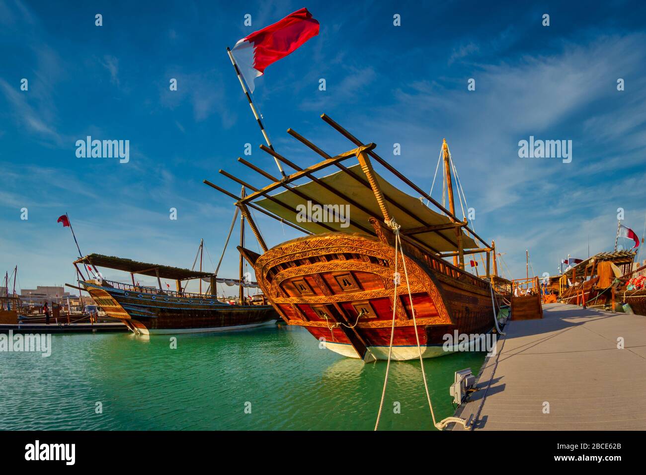 Bateaux en bois traditionnels (hurues) à Katara Beach Qatar vue de jour avec drapeau du Qatar et nuages dans le ciel Banque D'Images