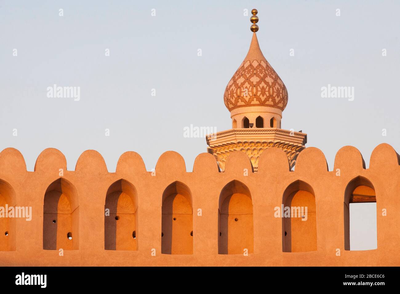 La tour et le dôme d'oignon d'une mosquée au-dessus des murs fortifiés du fort de Nizwa, Nizwa, Oman Banque D'Images