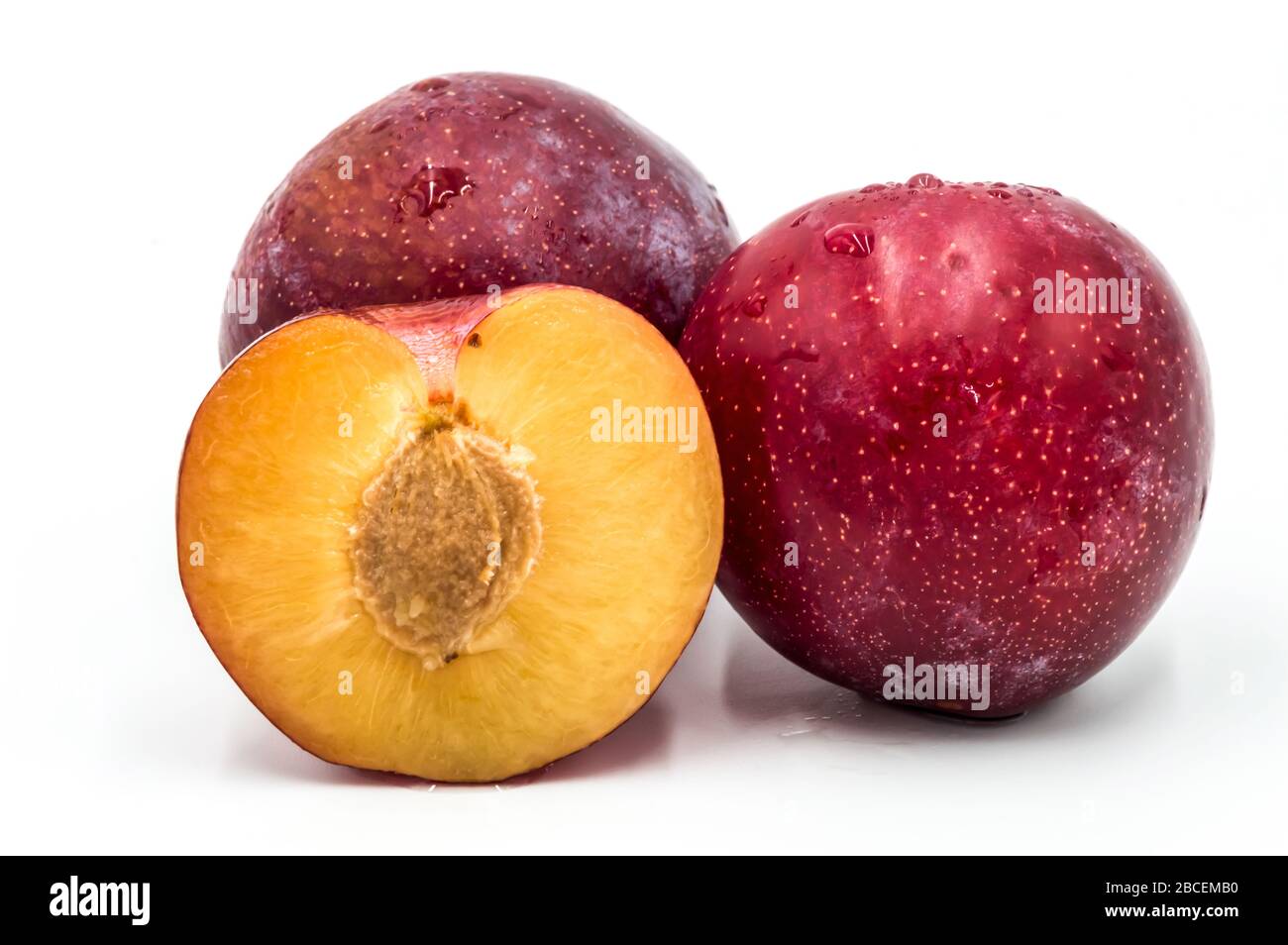 Prunes rondes rouges mûres et un quart isolées sur blanc. Grand plan Banque D'Images Prunes rondes rouges mûres et un quart isolées sur blanc. Grand plan Banque D'Images
