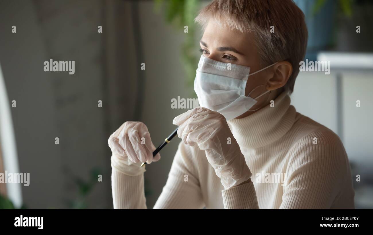 Jeune femme d'affaires pensive avec gants médicaux et masque facial de protection. Banque D'Images