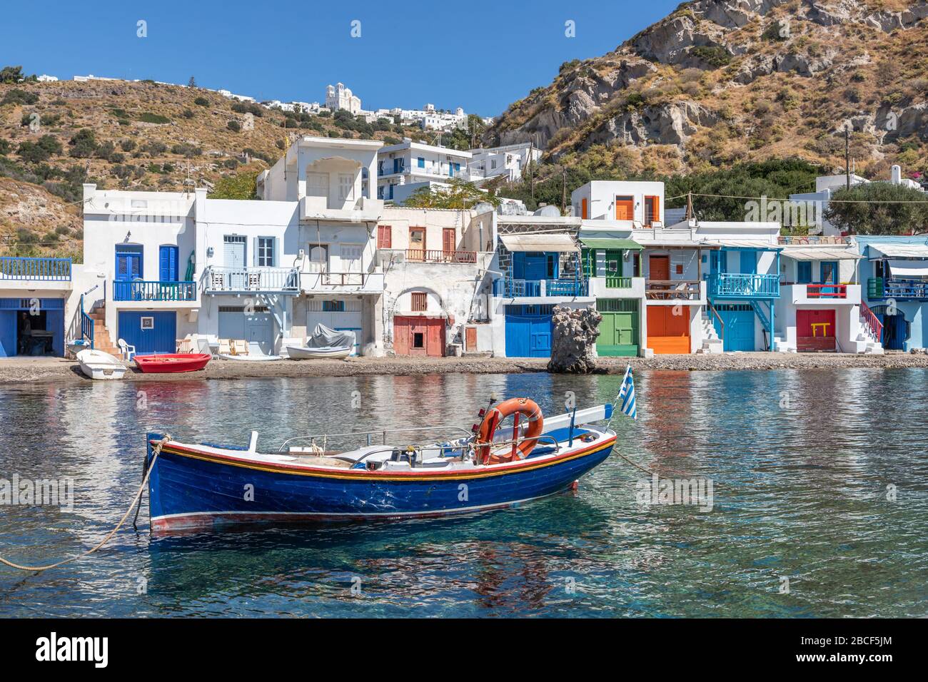 Maisons colorées en bateau à la plage de Klima avec le village de Trypiti en arrière-plan, Milos, Grèce Banque D'Images