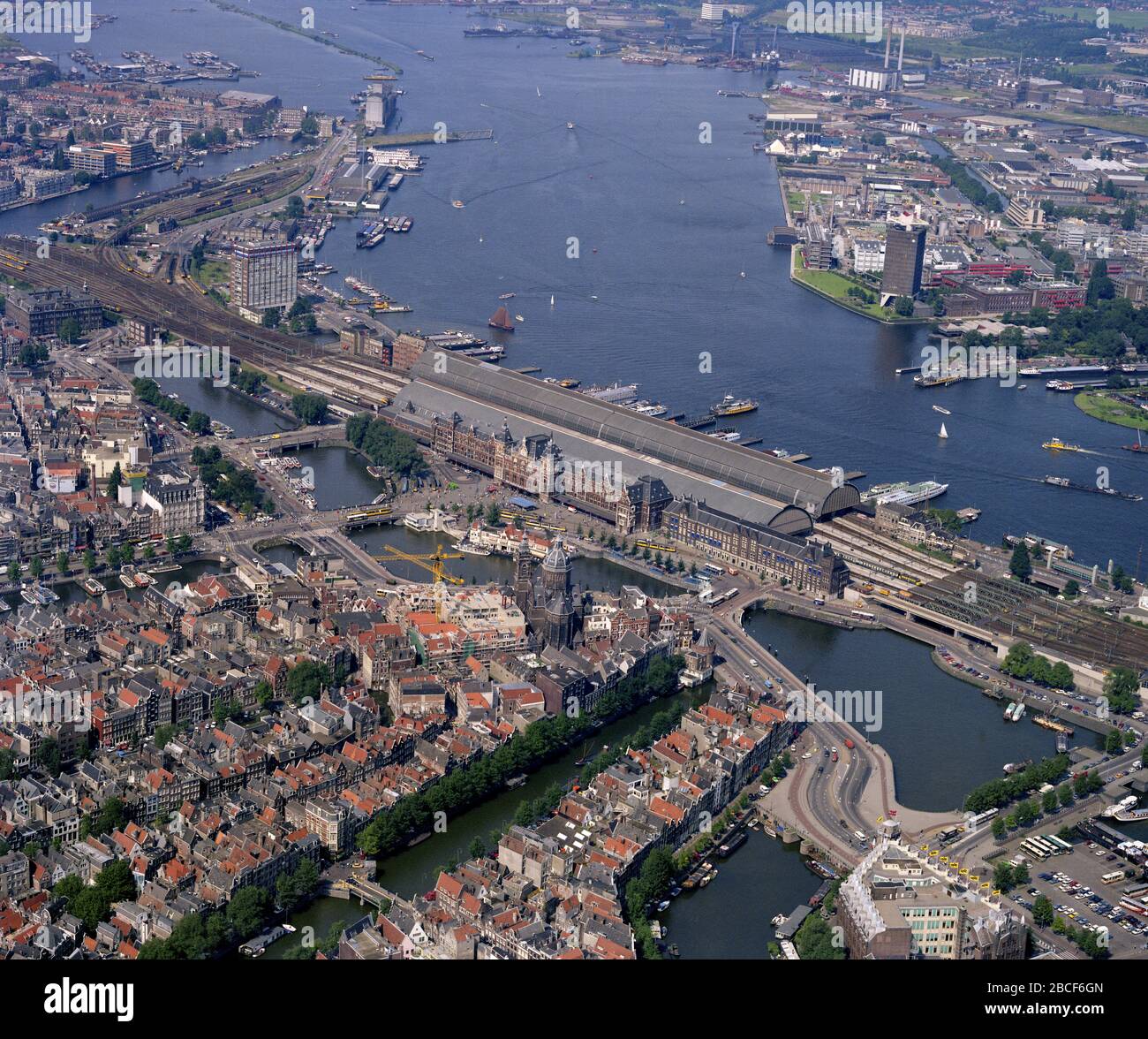 Amsterdam, Pays-Bas, 24 août - 1987 : photo aérienne historique de la gare centrale, de l'IJ et de la basilique Saint-Nicolas dans le centre d'Amsterdam Banque D'Images
