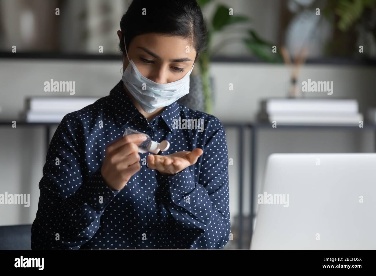 Femme indienne appliquant du gel antibactérien sur les mains. Banque D'Images