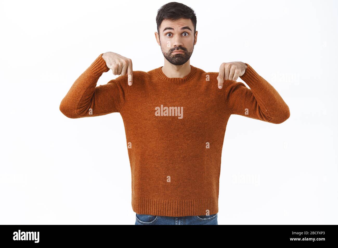 Portrait d'un homme barbu indécis posant des questions sur le produit, en pointant les doigts vers le bas et en regardant l'appareil photo incertain, en consultant avec la petite amie Banque D'Images